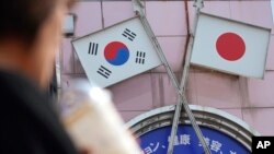 资料照：一名女子走过东京街头一家悬挂日韩国旗的商店。（2019年8月2日）