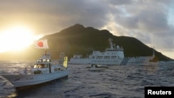 中国海监船（中）在东中国海域的钓鱼岛，日本称作尖阁列岛的有争议海岛旁航行，日本海岸警卫队的船只在旁（右与左船），前船为日本渔船。（2013年7月1日）