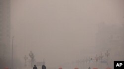 2012年1月18日两名行人走过被雾霾笼罩的北京街头