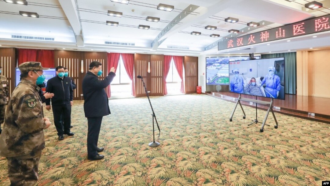 資料照：戴著口罩的中國國家主席習近平視察火神山醫院時通過視頻向新冠病毒感染者和醫護人員招手。 （2020年3月10日）