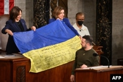 Президент України Володимир Зеленський дарує український прапор тодішній спікерці Палати представників США Ненсі Пелосі, а такожі віце-президентці США Камалі Гарріс під час виступу в Конгресі США, 21 грудня. 2022 р. (Jim WATSON/AFP)