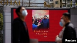 上海街头戴着口罩的行人走过宣传习近平的宣传画。（2020年3月23日）