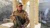 FILE - A fighter sits on top of a tombstone inside a 200-year-old monastery in the Christian village of Bakufa, 30 kilometers (18.6 miles) north of Mosul, Iraq, Nov. 12, 2014.