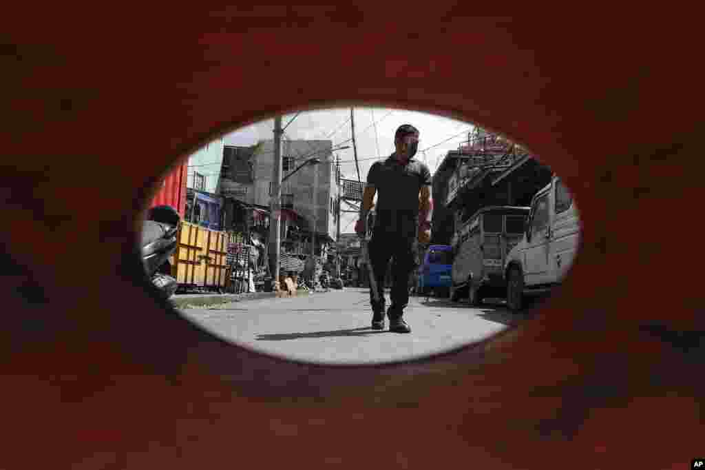 A policeman patrols inside a village under lockdown as the government implements stricter measures to prevent the spread of the coronavirus in Manila, Philippines.