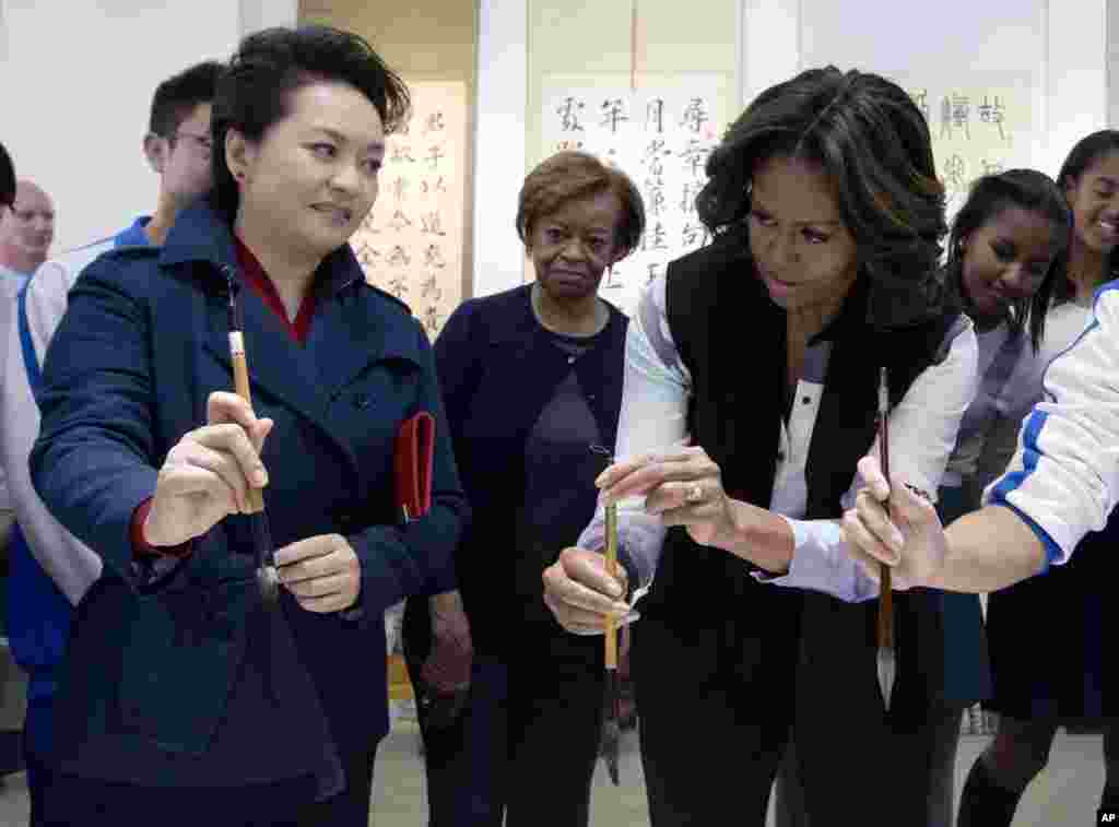 中国国家主席习近平的夫人彭丽媛3月21日向美国第一夫人米歇尔.奥巴马展示如何使用毛笔,当时她们在参观北京一所学校的中国书法课。
