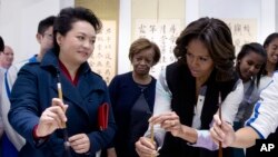 在参观书法课时，习近平夫人彭丽媛教美国第一夫人米歇尔·奥巴马怎样用毛笔写字