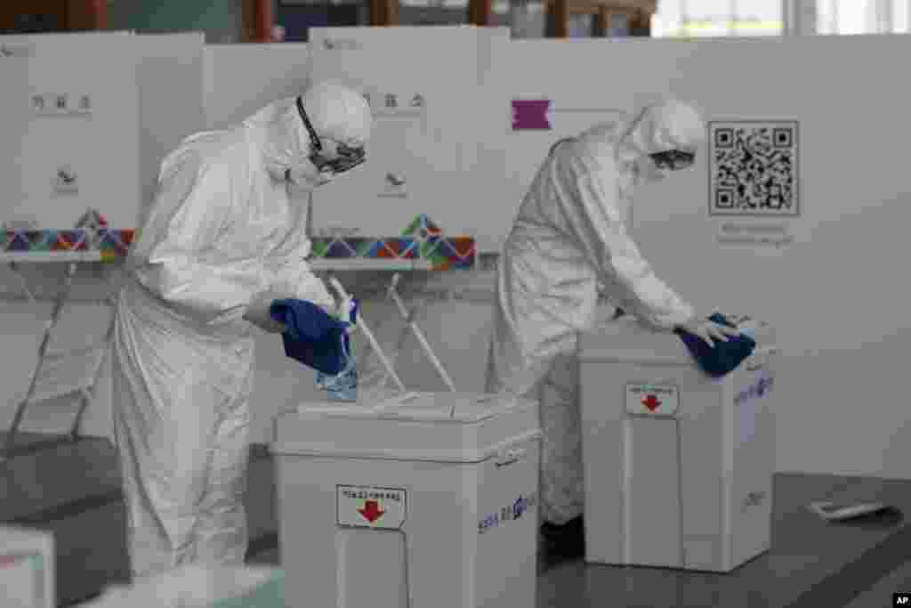 Workers wearing protective gears disinfect ballot boxes ahead of the early voting for the upcoming Seoul mayoral by-election at a local polling station in Seoul, South Korea.