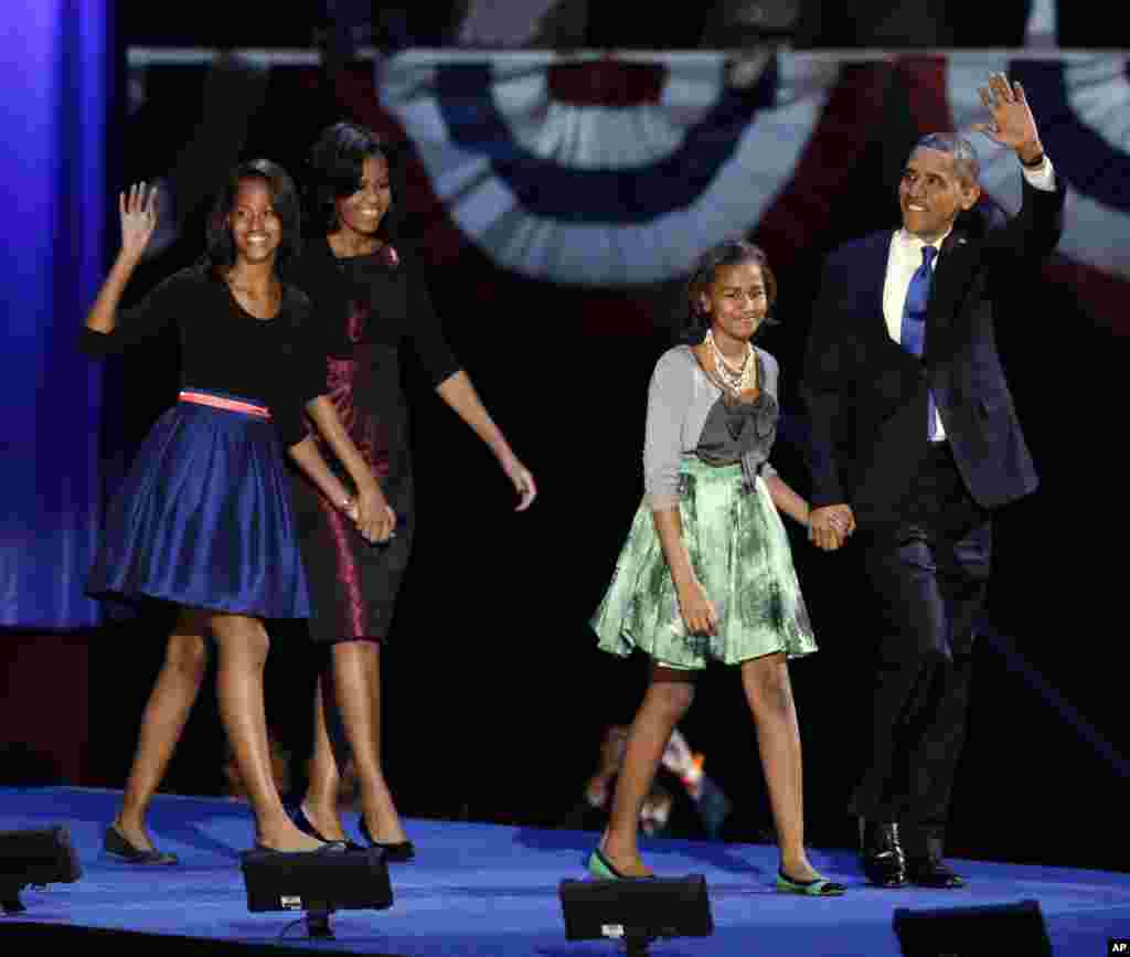Tổng thống Barack Obama cùng Đệ nhất phu nhân Michelle Obama và hai con gái Malia và Sasha vẫy chào người ủng hộ tại buổi lễ mừng chiến thắng của ông trong đêm bầu cử, ngày 7 tháng 1, 2012, tại thành phố Chicago, bang Illinois.