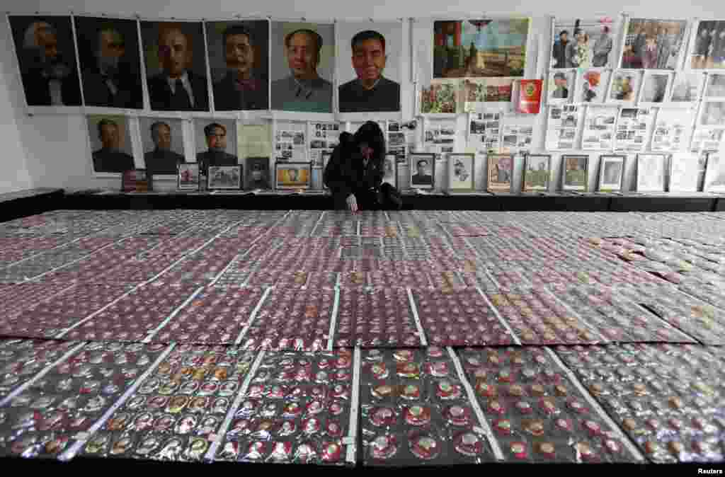 2011年11月29日,一位游客在中国云南省昆明市的一个红色博物馆观看毛泽东纪念章,墙上有马恩列斯毛和华国锋、刘少奇、周恩来和朱德的肖像。 