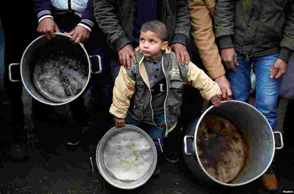 A Palestinian boy holds cooking pots during a protest against aid cuts, outside United Nations' offices in Gaza City.