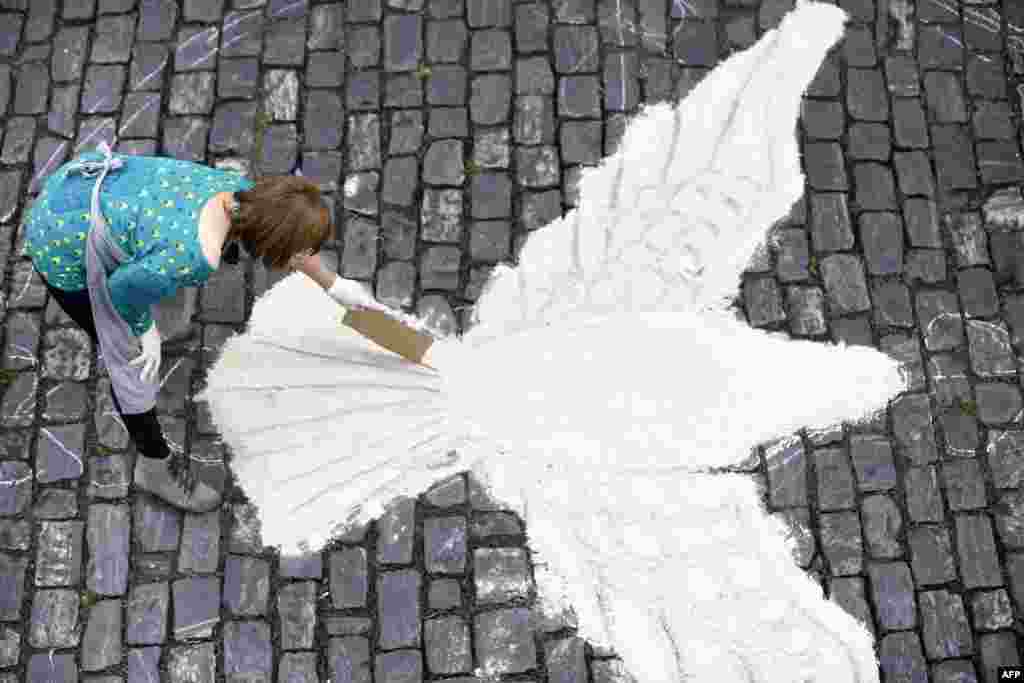 A woman takes part in the making of a sand and sawdust carpet for the Catholic Corpus Christi procession in a street of Mariana, some 120 km from Belo Horizonte, Brazil.
