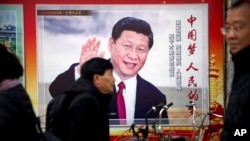2018年3月2日，中国北京，人们走过展示中国国家主席习近平的宣传广告牌。