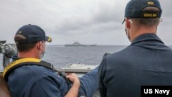资料照片：美国海军公布的照片显示，两位美国海军中校罗伯特·J·布里格斯与理查德·D·斯莱2021年4月4日在阿利·伯克级导弹驱逐舰“马斯廷号”驾驶舱进行水面接触观察。照片中可见中国"辽宁号"航空母舰及其舷号。