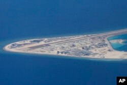 菲律宾空军一架运输机在南中国海南沙群岛的中国造的人造岛礁渚碧礁上空飞越时拍摄的照片，显示人造岛礁上的简易机场和建筑物。（2017年4月21日）