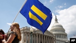 一名LGBT权利支持者举着“平等旗”参加民主党众议员乔·肯尼迪的集会，抗议特朗普总统不许跨性别者服役的禁令。(2017年7月26日）
