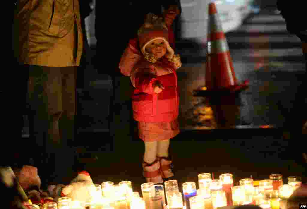 2012年12月16日,人们在一处临时纪念龛凭吊小学枪击案遇难者,一名小孩手指着蜡烛。