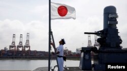 一名水手在日本加贺号直升机航母上升起日本国旗。（2018年9月30日）