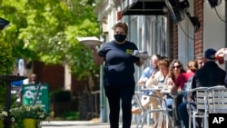 一名餐馆服务员在北卡罗来纳州教堂山的地中海熟食店的人行道上用餐的顾客上菜。上个季度，美国经济以6.4％的年增长率快速增长。