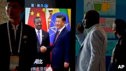 在北京举行中非合作论谈期间，非洲代表团成员走过正在播放中国国家主席习近平与埃塞俄比亚总理艾哈迈德握手的视频画面。（2018年9月3日）