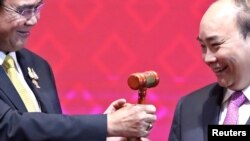 资料照片：在第35届东盟峰会及相关领导人会议的闭幕式上，越南总理阮春福从泰国首相巴育手中接过主席桘。