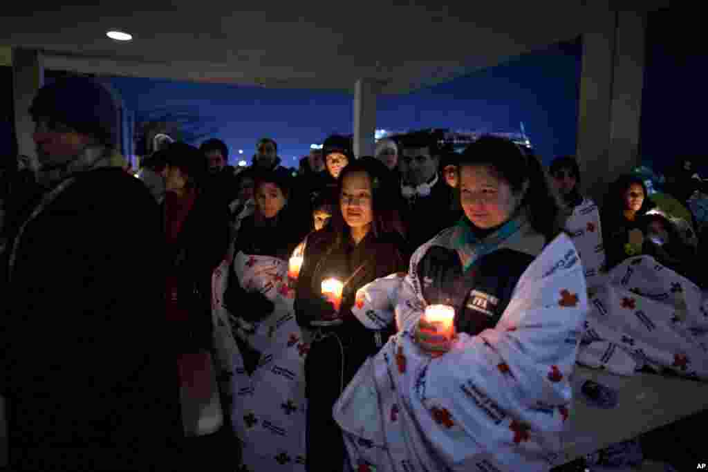 2012年12月16日,在奥巴马总统在纽敦高中举行的一次跨教派烛光守夜仪式上讲话之际,居民们在校外举着蜡烛纪念桑迪.胡克小学枪击案遇难者。