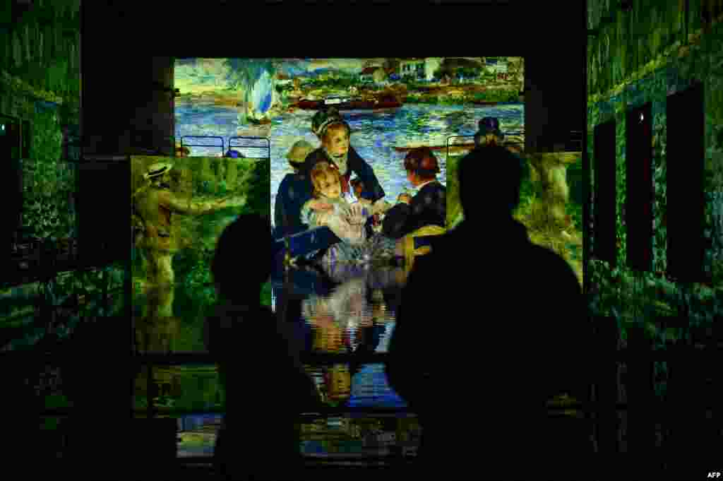 Journalists watch projections of paintings during a press visit of the digital exhibition entitled "Monet, Renoir, and Chagall: Journeys Around the Mediterranean" at the "Bassin des Lumieres" in a former German WWII submarine base in Bordeaux, France.