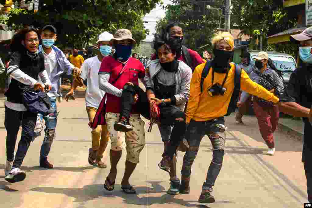 Protesters carry an injured comrade during a demonstration against the military coup in Yangon's Thaketa township, Myanmar.