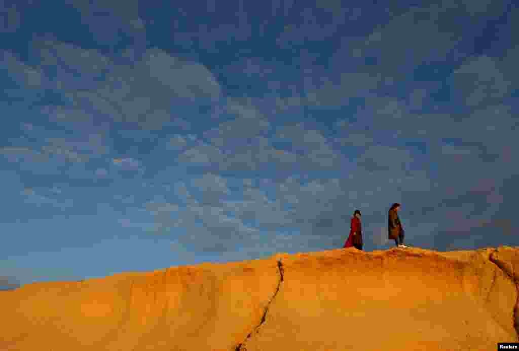 Tourists walk along the coastline at Dwejra outside the village of San Lawrenz on the island of Gozo, Malta.