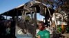 A supporter of the ruling ZANU-PF walks past a burnt vehicle at the party's offices a day after the clashes between security forces and opposition protesters in Harare, August 2, 2018. 