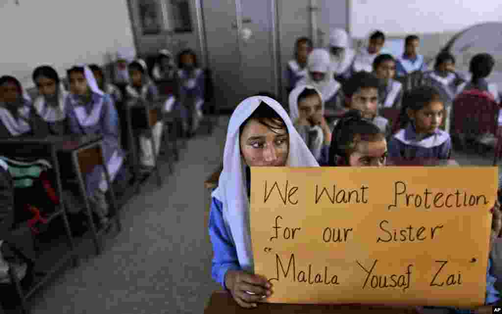Nữ sinh Pakistan cầm poster với hàng chữ "Chúng tôi muốn Malala Yousufzai được bảo vệ" trong khi giáo viên kể chuyện về Malala ở Islamabad, Pakistan, ngày 12 tháng 10, 2012.