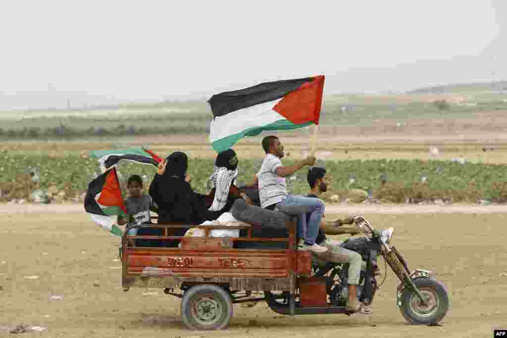 Palestinian protesters wave national flags as they transport tyres on a motorcycle car to burn them during protests near the border fence between Israel and the Gaza Strip, on the eastern outskirts of Jabalia.