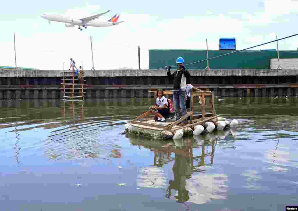 A man holds onto a rope as he takes children to a school on a makeshift raft across a river in Paranaque city, south of Manila, Philippines.