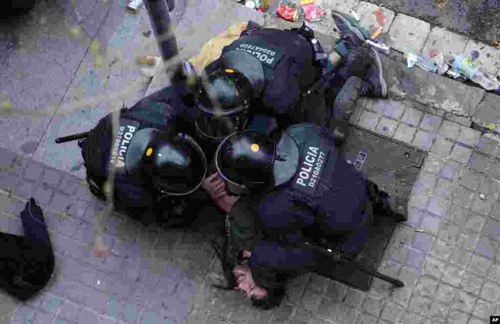 Catalan Mossos d'Esquadra regional police officers detain a man during clashes with pro-independence supporters trying to reach the Spanish government office in Barcelona, Spain.