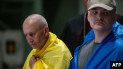 На цій роздатковій фотографії, оприлюдненій пресслужбою Міноборони України в Києві 29 червня 2024 р., зображений священник УГКЦ Богдан Гелета (ліворуч) серед громадян України, які повернулися з російського полону після обміну полоненими. (Фото: пресслужба Міноборони України/AFP)