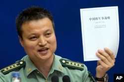 中国国防部发言人杨宇军手持《中国的军事战略》白皮书在新闻发布会上（2015年5月26日）