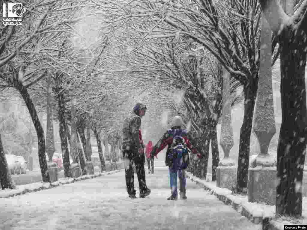 2013年1月9日,叙利亚人在雪中走过霍姆斯的古塔区。(Lens Young Homsi)