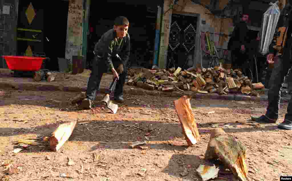 Bé trai chặt củi để sưởi ấm tại thành phố Aleppo, Syria, ngày 28/12/2012.