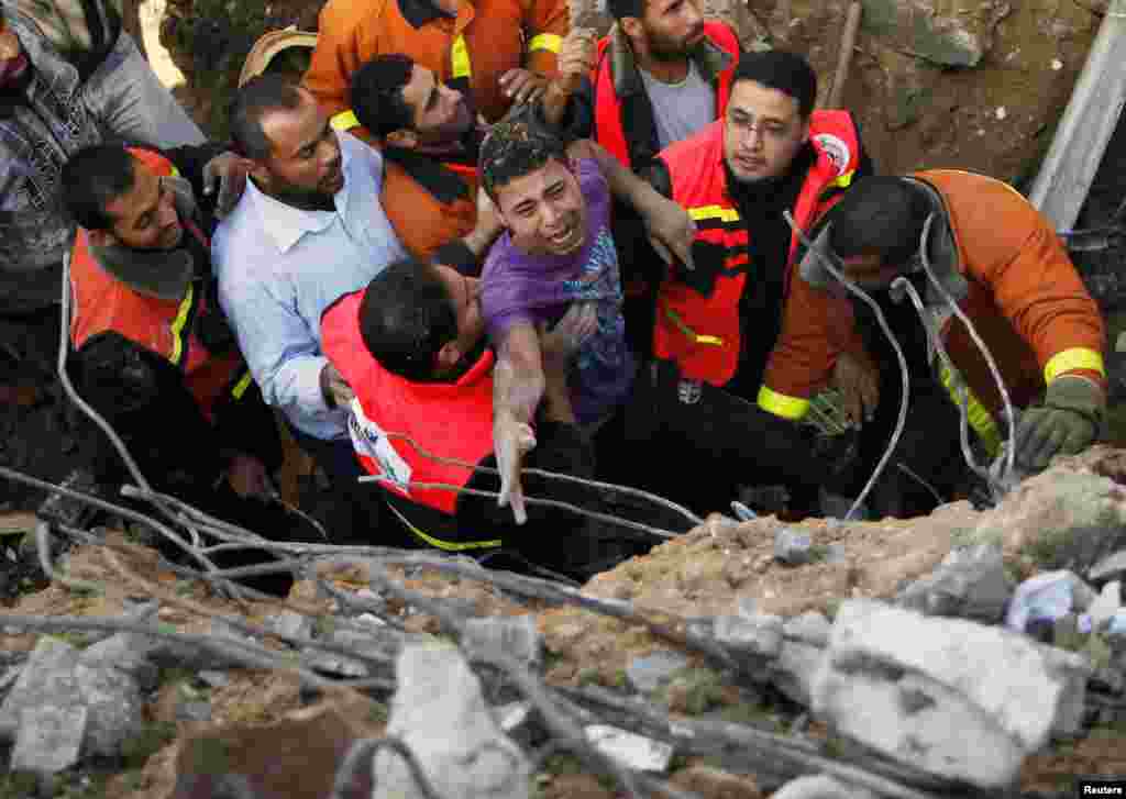 Các thành viên Quốc phòng Dân sự Palestine giúp người sống sót sau khi ông được lôi ra từ dưới đống đổ nát của ngôi nhà bị phá hủy sau cuộc không kích của Israel vào thành phố Gaza, ngày 18/11/2012.