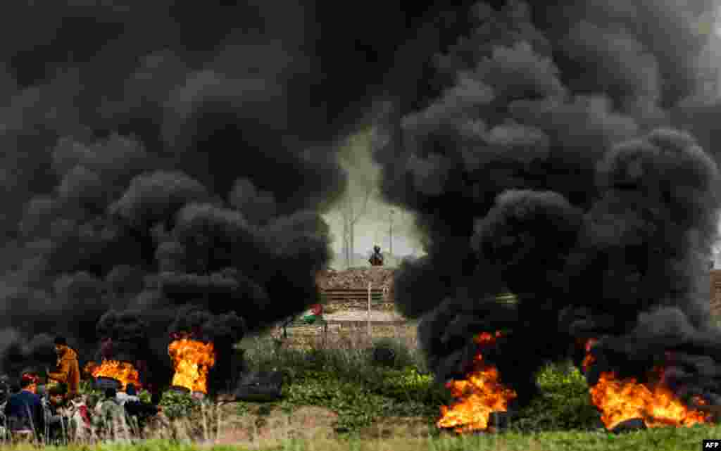 Palestinian protesters run amid the smoke during clashes with Israeli forces near the border with Israel east of Gaza city on February 9, 2018.