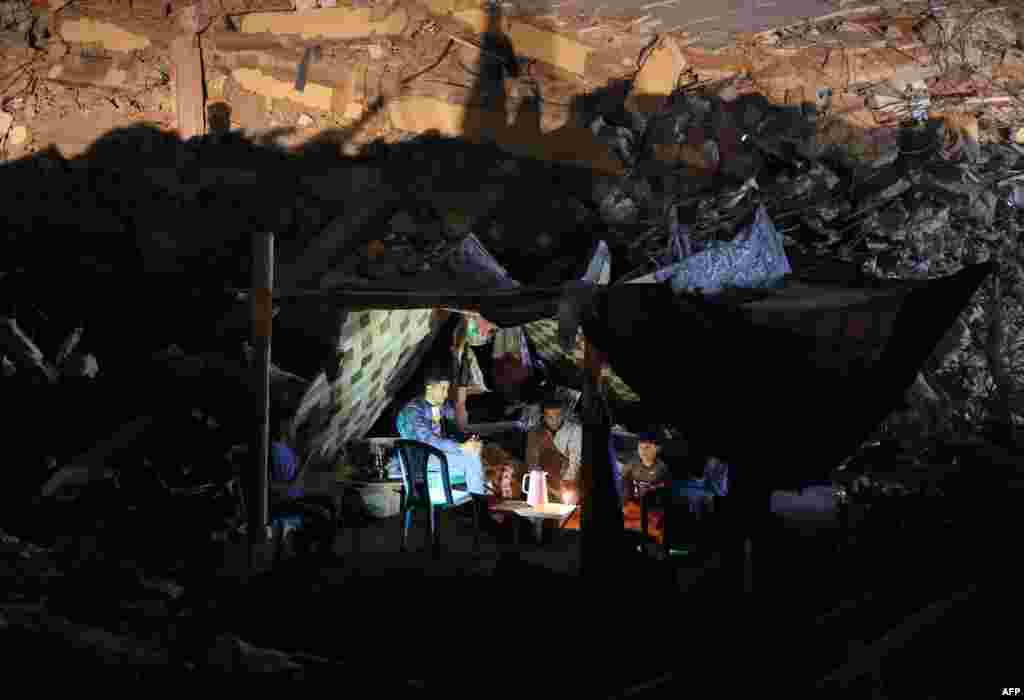 Palestinians sit in a tent that has been set up on top of the ruins of a building destroyed in recent Israeli airstrikes, in Gaza City, May 24, 2021.