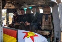 Former president Robert Mugabe's two sons Chatunga Mugabe, center, and Robert Mugabe Junior, right, accompany his casket in an air force helicopter for transport to a stadium where it will lie in state, in Harare, Zimbabwe, Sept. 13, 2019.