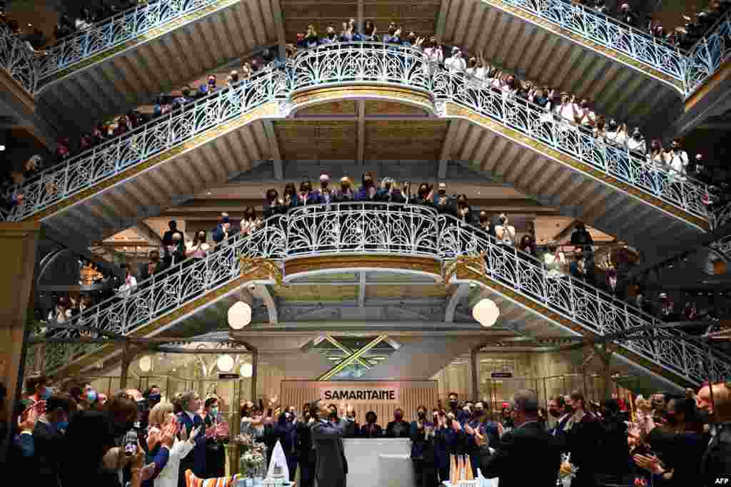 French President Emmanuel Macron (C) and employees of Paris' iconic department store La Samaritaine applaud during a ceremony marking the store's reopening after 16 years of closure.