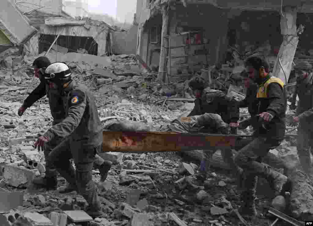 Members of the Syrian civil defense evacuate an injured civilian from an area hit by a reported government airstrike in the rebel-held town of Saqba, in the besieged Eastern Ghouta region on the outskirts of the capital Damas.
