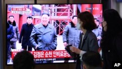 人们在电视上观看有关朝鲜领导人金正恩出席竣工仪式的新闻节目。