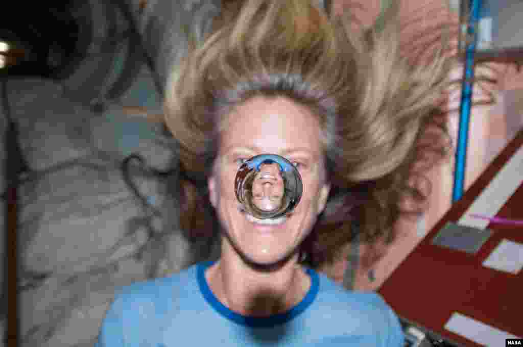 NASA astronaut Karen Nyberg watches a water bubble float freely between her and the camera, showing her image refracted in the droplet, Feb. 7, 2018.