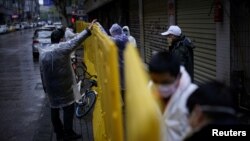 湖北省武汉市是中国冠状病毒病爆发的重灾区，戴着口罩的工人们正在修复街道上的障碍物。（2020年3月29日）