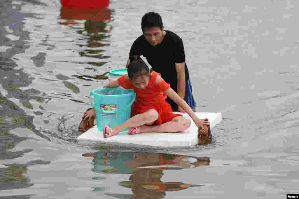 2018年9月2日,中国广东省汕头市一个小镇,暴雨过后,男子蹚水穿过一条被水淹没的街道,推着泡沫塑料板上的女孩,女孩拿着拖鞋。RFA9月4日报道:“ 广东省汕头市遭遇洪水袭击6天之后,潮南区多个乡镇数十万民众,周二(4日)依然被洪水围困,官方救援不力引发网上恶评如潮,各地志愿者倾力相救但依然面对困难重重。 ”但中新网汕头9月5日报道, 汕头市潮阳区谷饶镇罕见的水灾,“在广东各级部门紧急调拨抽水设备强力排涝后,已从最高峰时期的2米水深,到目前平均水深只有30厘米。 ”“ 尽管积水已逐渐退去,当地官方仍在持续全力抗灾救灾。 ”