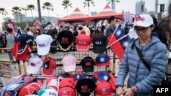 2024年1月7日，总统大选前一周，高雄，一名街头小贩在主要反对党国民党的竞选集会上出售旗帜和帽子。（法新社）