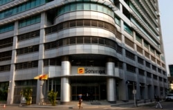 FILE - A woman walks past the head office of Angolan state oil company Sonangol in Luanda, Aug. 26, 2012.