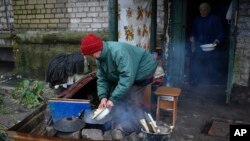 Фото: жінка готує на вогні в місті Лиман, Донецької області, 20 листопада 2022 року. AP Photo/Andriy Andriyenko
